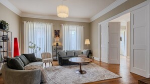 Ett vardagsrum med en soffa, fåtöljer, ett soffbord och en lampa.
