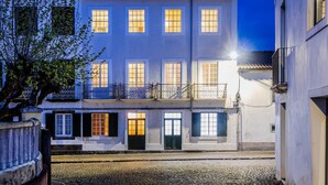 En byggnad med flera våningar och en innergård, som har en traditionell arkitektonisk stil med vita väggar och mörka fönsterluckor.