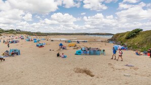 Ein Strand mit Zelten und Menschen, sandigem Untergrund und blauem Himmel.