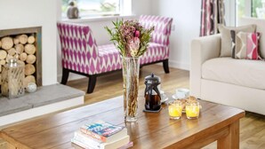 Ein Holztisch mit Büchern, einer Vase mit Blumen, einem Teekessel und Gläsern Orangensaft.