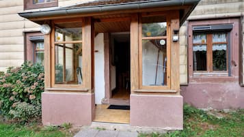 A building with a wooden porch, large windows, and a door leading to an interior space.