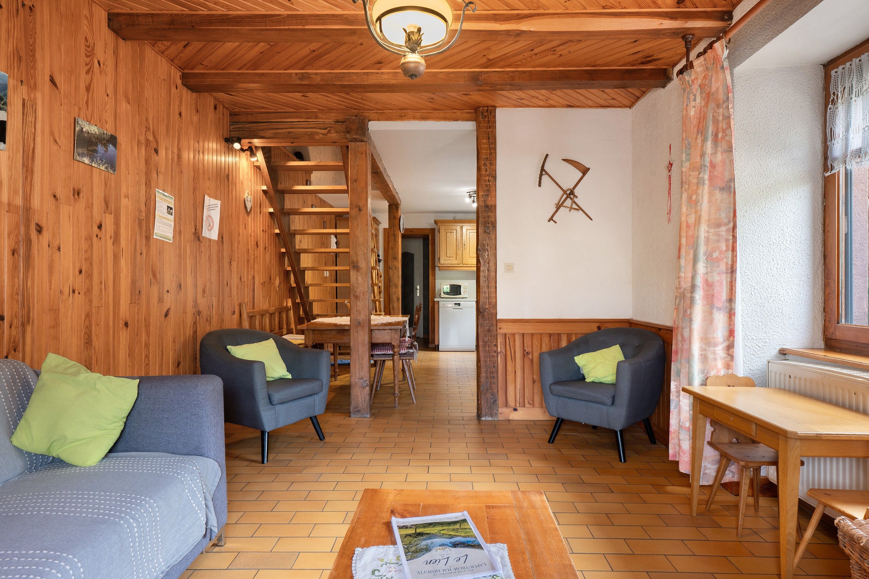 Ein gemütliches Interieur mit Holzwänden, einer Treppe, einem Essbereich und einer Küche im Hintergrund.