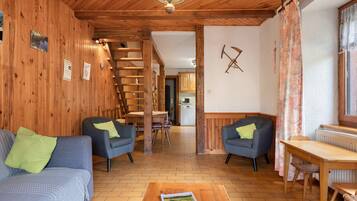 Ein gemütliches Interieur mit Holzwänden, einer Treppe, einem Essbereich und einer Küche im Hintergrund.