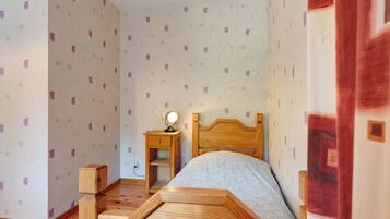 Une chambre à coucher avec un lit en bois, une table de chevet avec une lampe et un papier peint à motifs.
