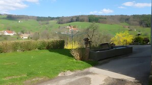 A rural landscape with a road, green fields, and a few houses.