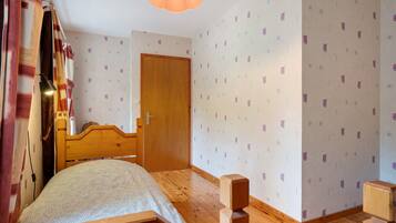Une chambre à coucher avec un lit en bois, une porte et un papier peint à motifs.
