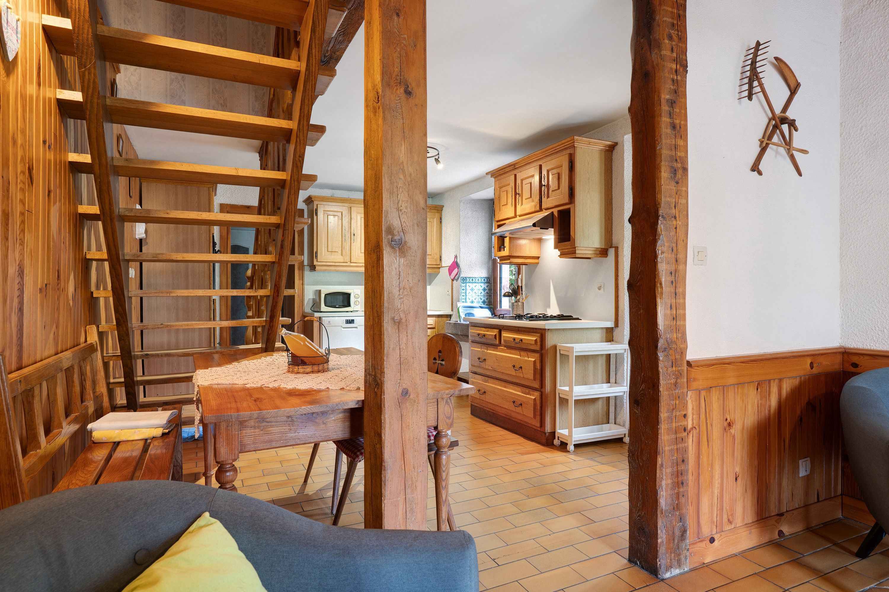 Un interior rústico con una escalera de madera, una zona de comedor y armarios de cocina.