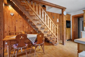 A wooden interior with a staircase, a dining table with chairs, and a kitchen area. - Gîte les hambostures (Lapoutroie)