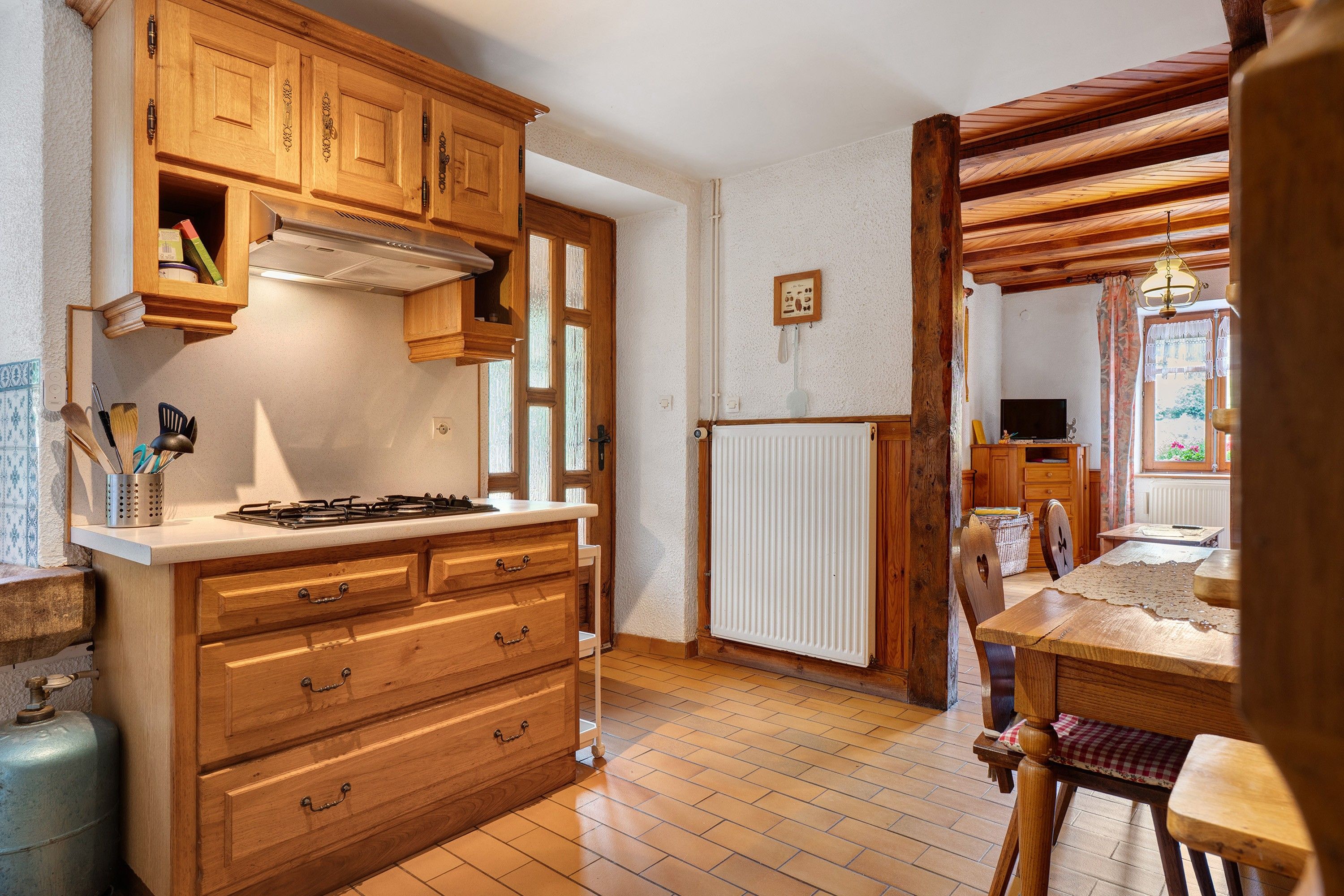 Una cocina con armarios de madera, estufa a gas y encimera blanca.