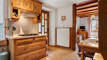 Una cocina con armarios de madera, estufa a gas y encimera blanca.