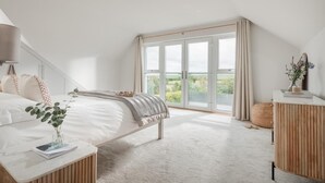 A bedroom with a bed, bedside tables, a window, and a view of greenery. - 5 Bed in St. Minver (oc-l50188) (Saint Minver)