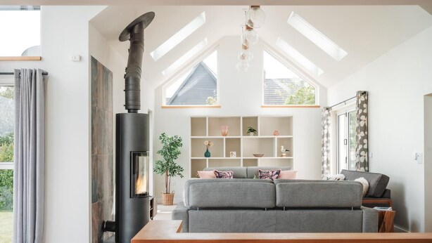 A modern living room with a fireplace, a sofa, a wooden coffee table, and a built-in shelf with decorative items. - 5 Bed in St. Minver (oc-l50188) (Saint Minver)