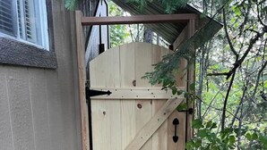 Una reja de madera con un diseño diagonal, un pestillo metálico y una puerta pequeña.