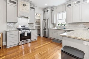 A modern kitchen with white cabinets, stainless steel appliances, and a granite countertop. - Charming Irish Channel 3BR- Minutes to French Quarter (New Orleans)