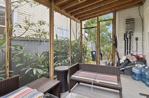 A covered patio with wicker furniture, a water heater, and a wooden ceiling. - Charming Irish Channel 3BR- Minutes to French Quarter (New Orleans)