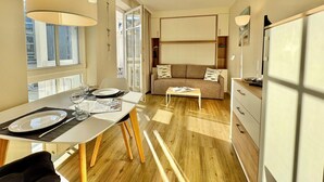 A modern living room with a sofa, a coffee table, and a dining area with a table set for two. - Komfortables Studio mit Balkon in Sellin (Sellin)