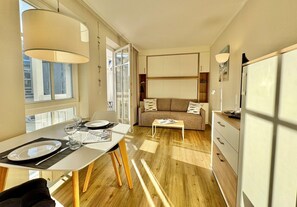 Ein modernes Wohnzimmer mit Sofa, Couchtisch und Essbereich mit Tisch für zwei Personen.
