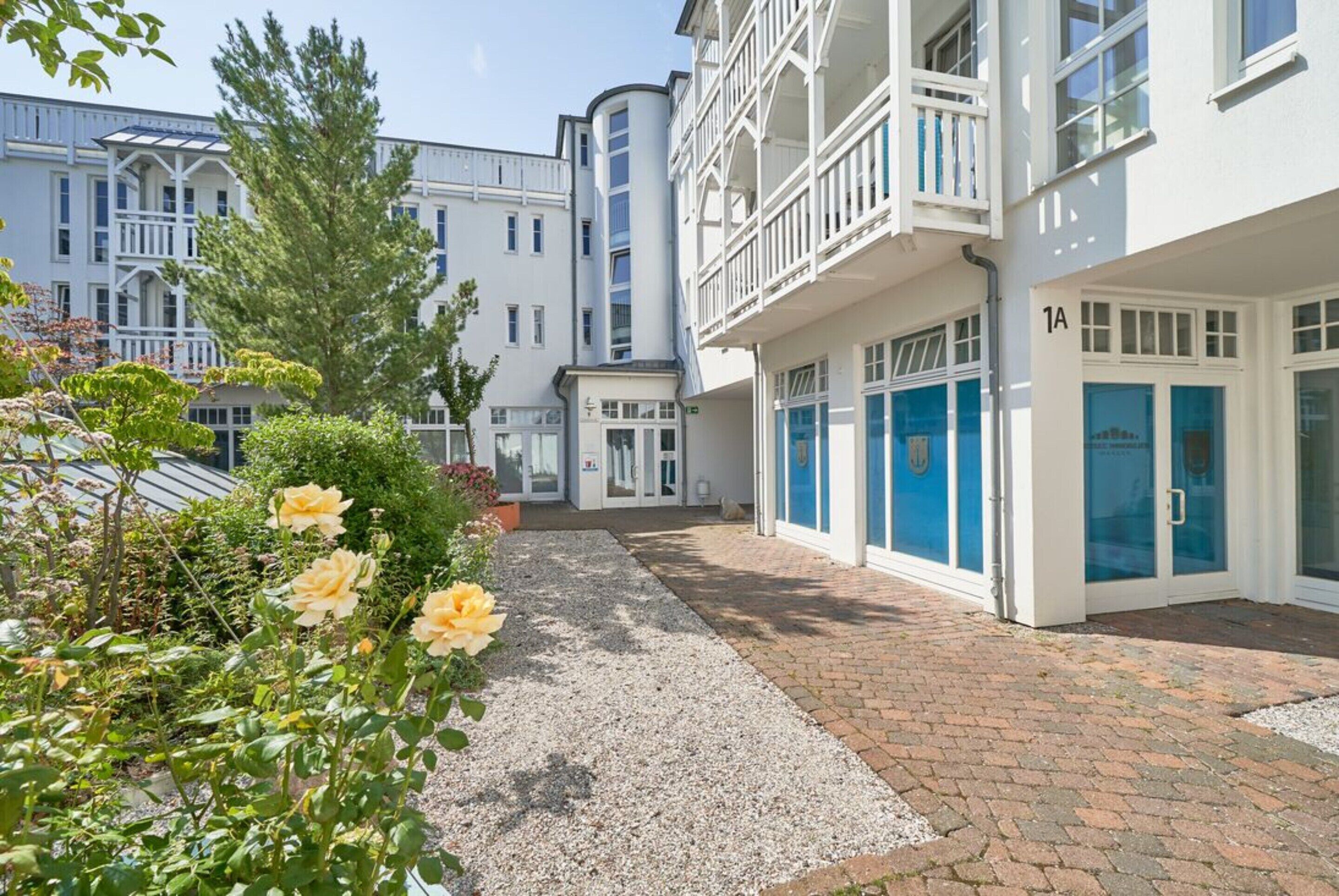 Et hotel med en grussti, en rosenhave og en bygning med balkon.