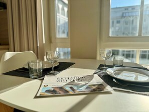 A dining table with a newspaper, glasses, and a plate. - Komfortables Studio mit Balkon in Sellin (Sellin)