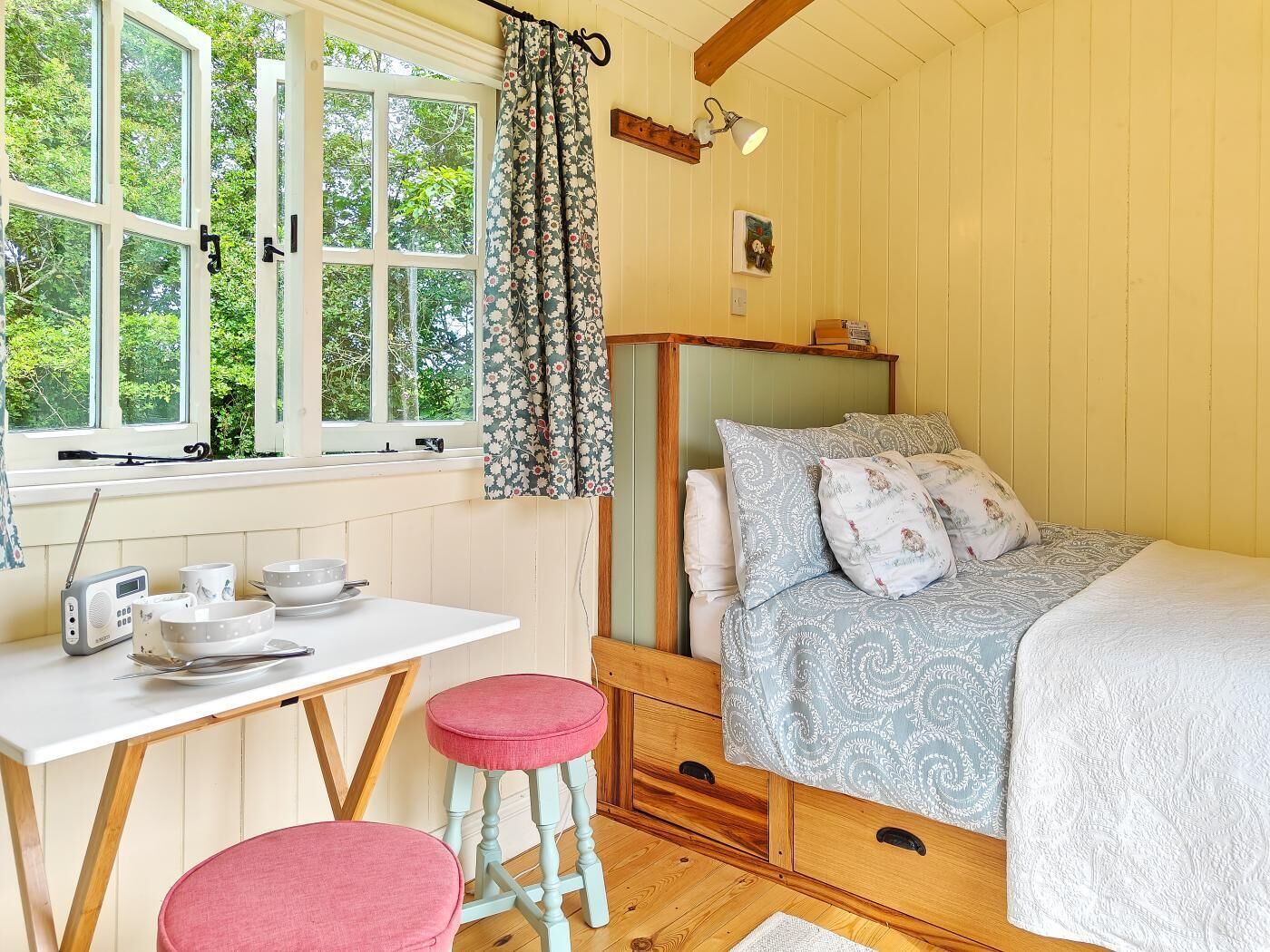 Un dormitorio con cama, mesita de noche y ventana con cortinas.