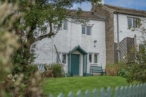 A white building with a green door, a small porch, and a bench. - 2 Bed in Bradley (oc-w44709) (Skipton)
