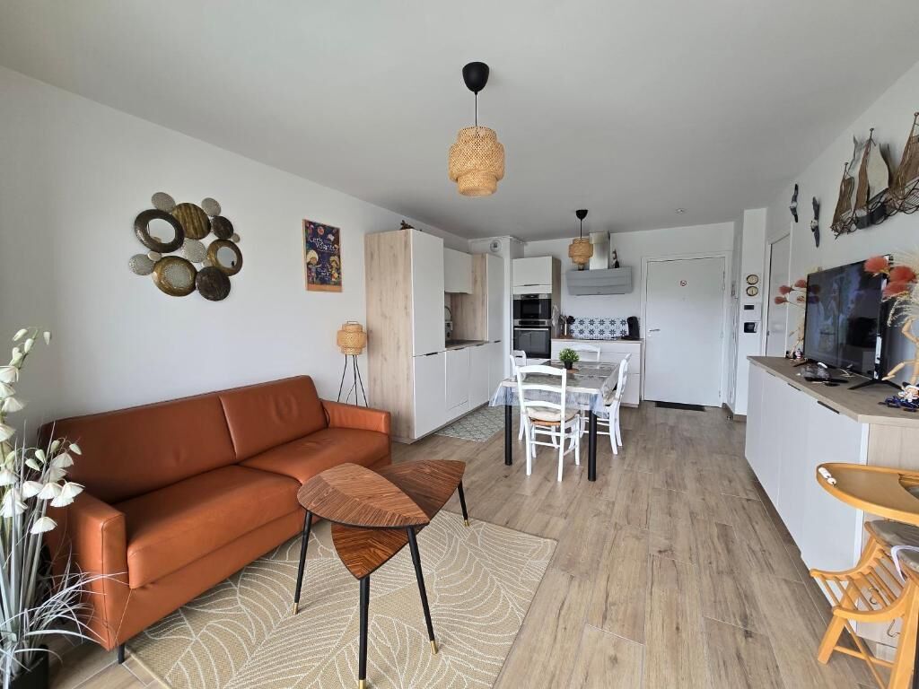 A modern living room with a sofa, a coffee table, and a dining area with chairs and a table.