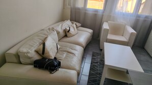 A room with a beige sofa, a small white table, and a black bag on the sofa. - Just a short walk from Avignon's historic center, a quiet apartment, (Avignon)