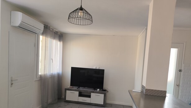 A modern kitchen with a flat-screen TV, a pendant light, and a sliding door. - Just a short walk from Avignon's historic center, a quiet apartment, (Avignon)