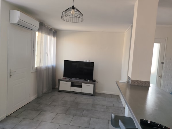 Eine moderne Küche mit Flachbildfernseher, einer Pendelleuchte und einer Schiebetür.