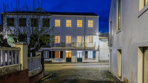A building with multiple windows, a gated entrance, and a cobblestone courtyard. - GuestReady - Doctor House Gardens (Horta)