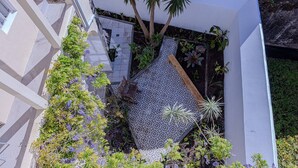 A rooftop garden with a patterned floor, a wooden bench, and various plants. - GuestReady - Doctor House Gardens (Horta)