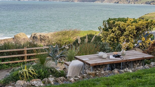 A coastal view with a wooden table and chairs, a vase, and a book on a table. - 2 Bed in Port Isaac (oc-l50168) (Port Isaac)