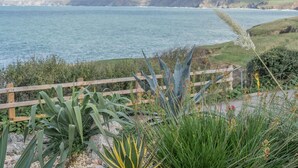 A coastal landscape with a wooden fence, various plants, and a view of the sea. - 2 Bed in Port Isaac (oc-l50105) (Port Isaac)