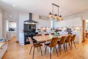A modern kitchen with a central island, a stove, and a dining area with chairs. - 7 Bed in Awre (oc-b42471) (Awre)