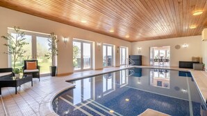 An indoor swimming pool with a wooden ceiling, large windows, and a seating area with chairs and a table. - 7 Bed in Awre (oc-b42471) (Awre)