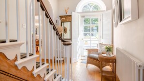 A staircase with white railings and a wooden handrail, leading to a room with a wicker chair and a table with a vase. - 7 Bed in Awre (oc-b42471) (Awre)