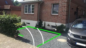 Ein zweistöckiges Backsteingebäude mit geneigtem Dach, einer Garage und einer Auffahrt mit einer grünen Markierung.