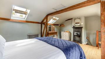 A bedroom with a bed, a dresser, a mirror, a radiator, and a fireplace.