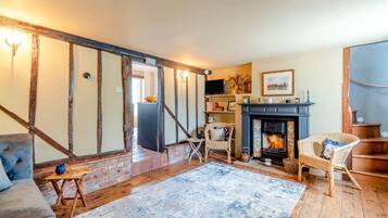A cozy living room with exposed wooden beams, a fireplace, and a comfortable seating area.