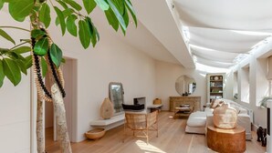 Uma sala de estar ampla com uma grande janela, um sofá, uma mesa de centro e um espaço de jantar.