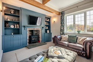 A living room with a fireplace, a leather sofa, and a television. - 4 Bed in Keswick (oc-s42744) (Keswick)
