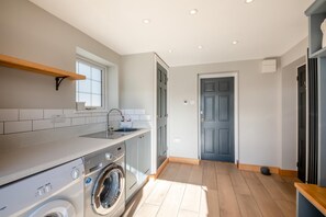 Eine moderne Küche mit Waschmaschine, Spüle und Fenster.