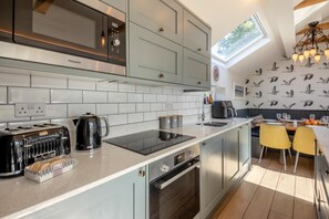 Eine moderne Küche mit integriertem Mikrowellenherd, Toaster und Wasserkocher, einem großen Fenster und einem Essbereich mit gelben Stühlen.