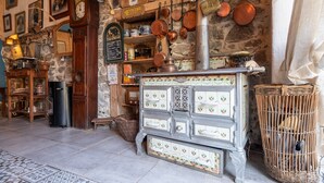 Ein rustikales Interieur mit Steinwand, Holzuhr und Kachelofen.