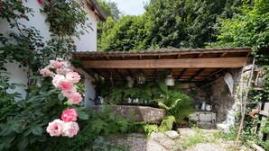Ein rustikaler Garten mit einer Holzpergola, üppigem Grün und vielfältigen Pflanzen.