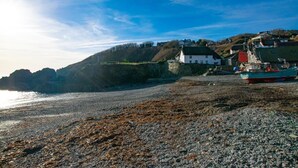 A rocky beach with a fishing boat, houses on a hillside, and a clear sky. - 1 Bed in Ruan Minor (oc-rencot) (Ruan Minor)