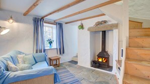 A cozy room with a sofa, a small table, a fireplace, and a staircase. - 1 Bed in Ruan Minor (oc-rencot) (Ruan Minor)