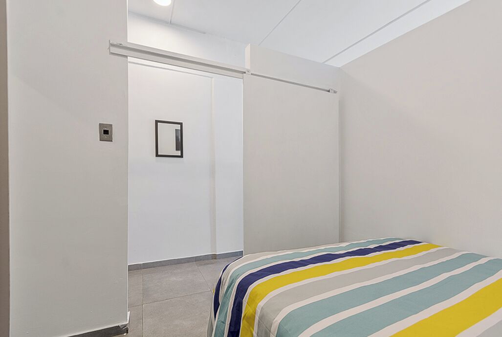 A bedroom with a bed, a door, and a light fixture.