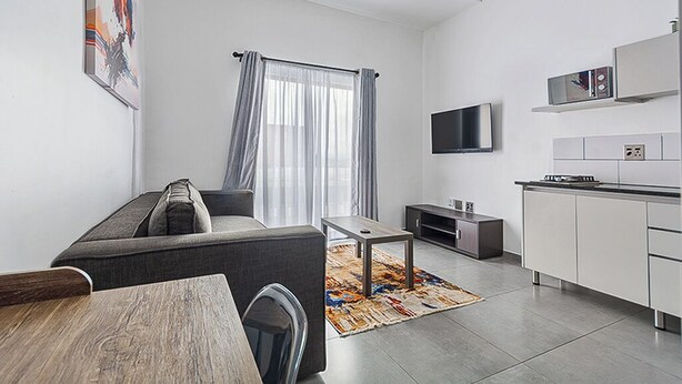 Ein modernes Wohnzimmer mit Sofa, Fernseher und Küchenbereich.