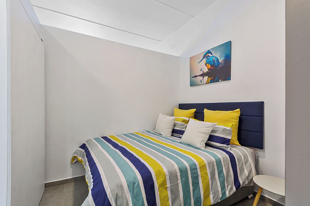 Ein Schlafzimmer mit einem Bett, Kissen, einem Kopfteil, einem runden Tisch und einem Bild an der Wand.